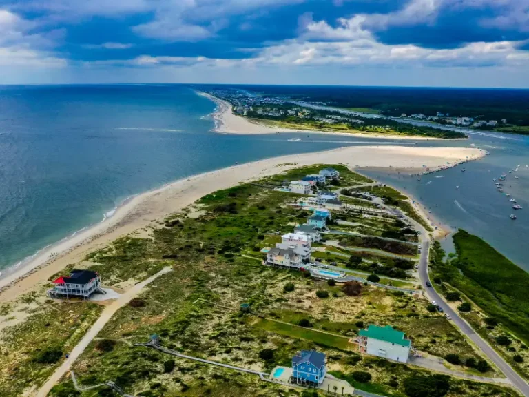 Aerial view of a coastal peninsula with houses, sandy beaches, and boats in the water.